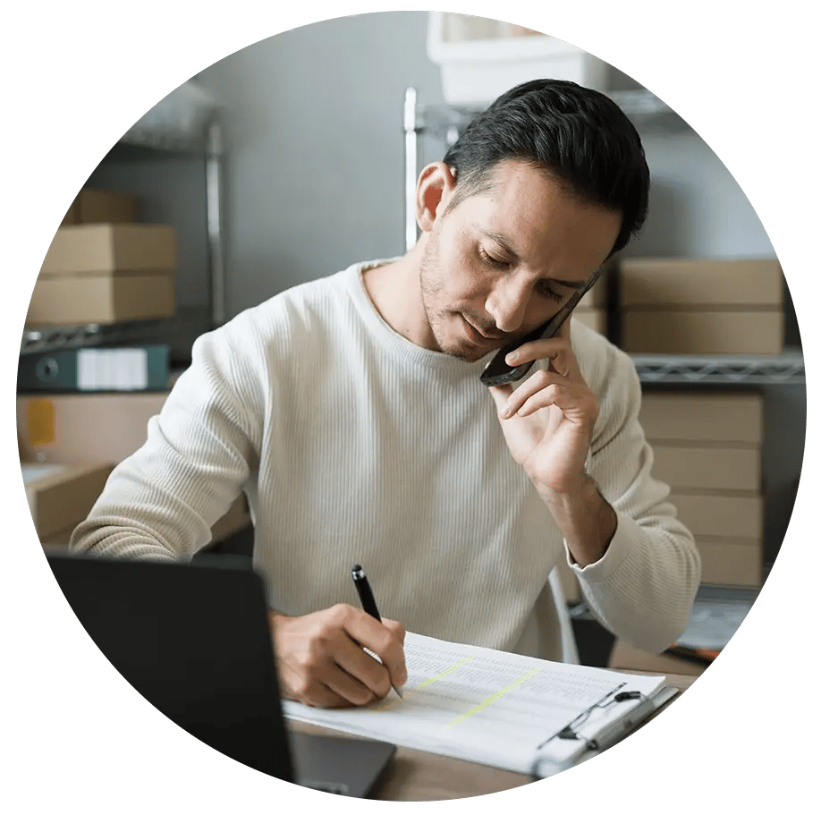 Man filling out document and talking on phone. 